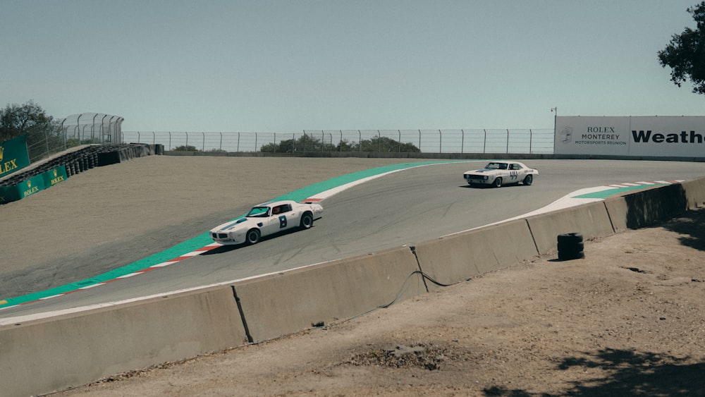 um par de carros dirigindo em uma pista de corrida