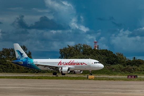 A sleek Kush Air passenger plane taxiing on a sunny runway surrounded by lush greenery.
