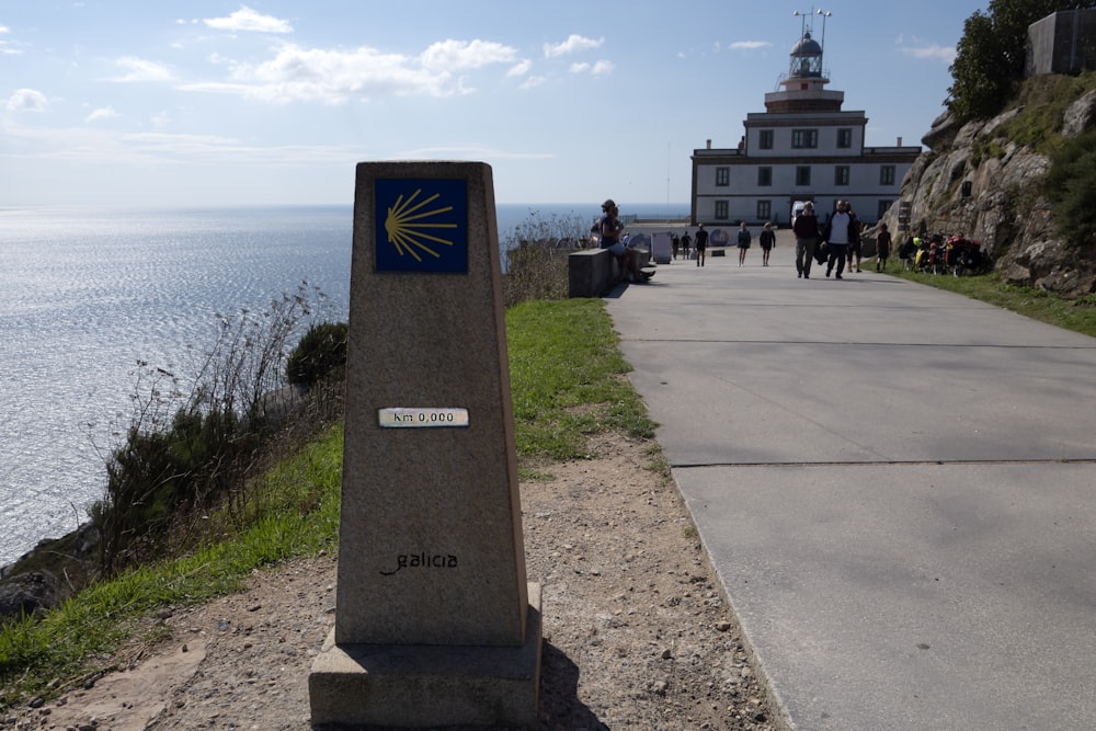 a stone pillar with a sign on it by a body of water