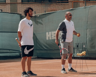 a couple of men stand on a tennis court