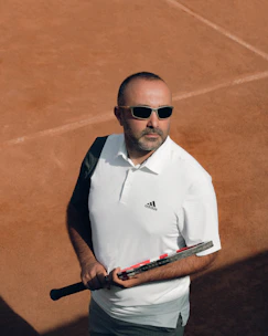 A focused young player practicing a powerful forehand on a sunlit tennis court.