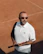 A focused man preparing to serve on an outdoor tennis court.