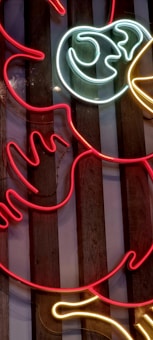 Colorful neon lights are shaped into abstract patterns against a backdrop of vertical wooden planks.
