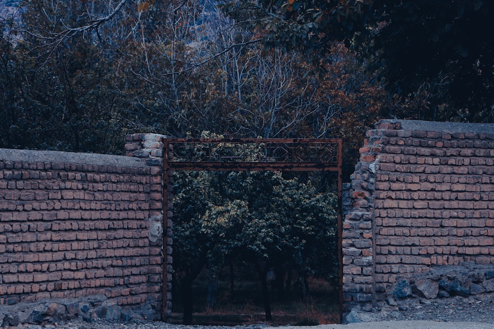a gate with a brick wall and a brick wall with trees in the background