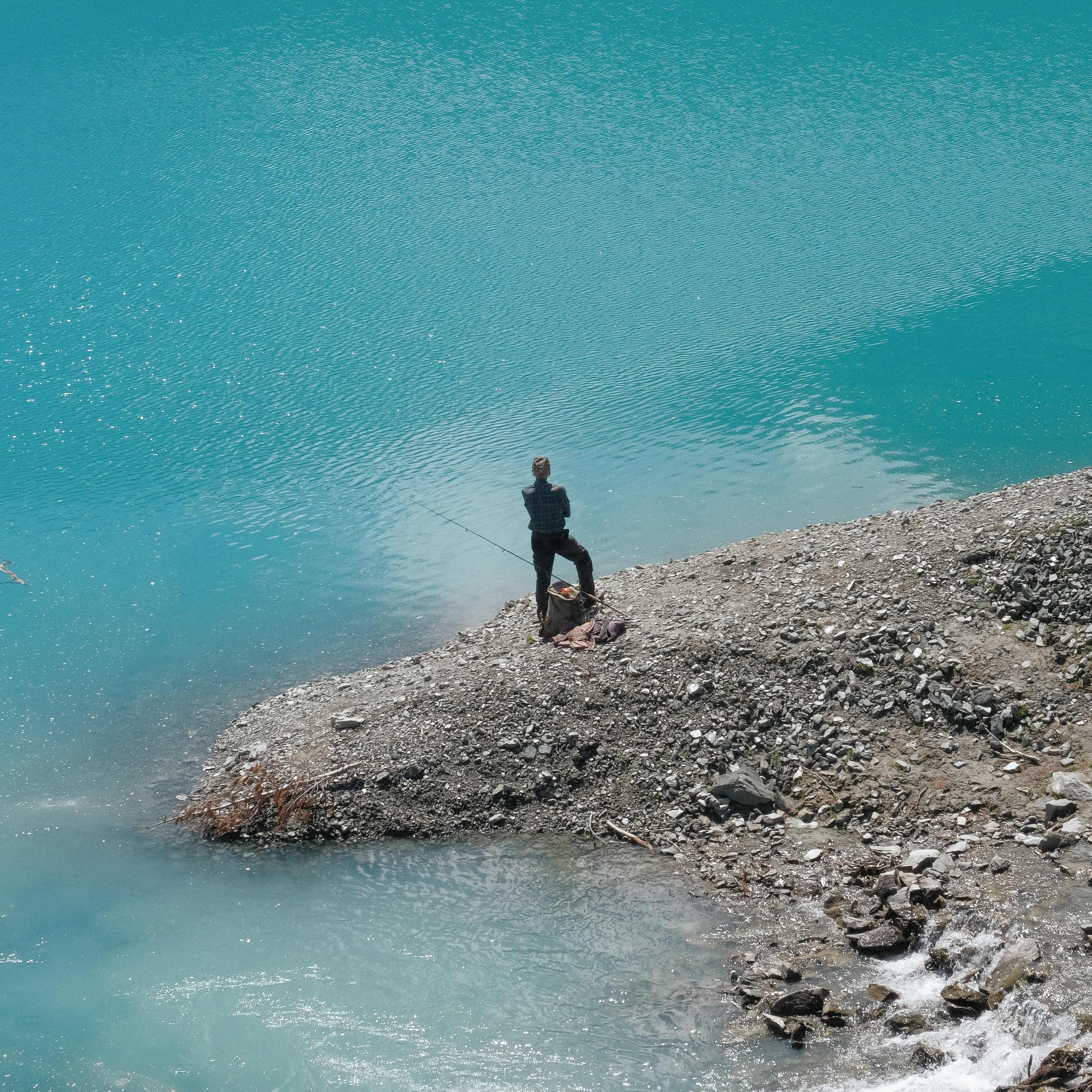 a person fishing on a rocky shore