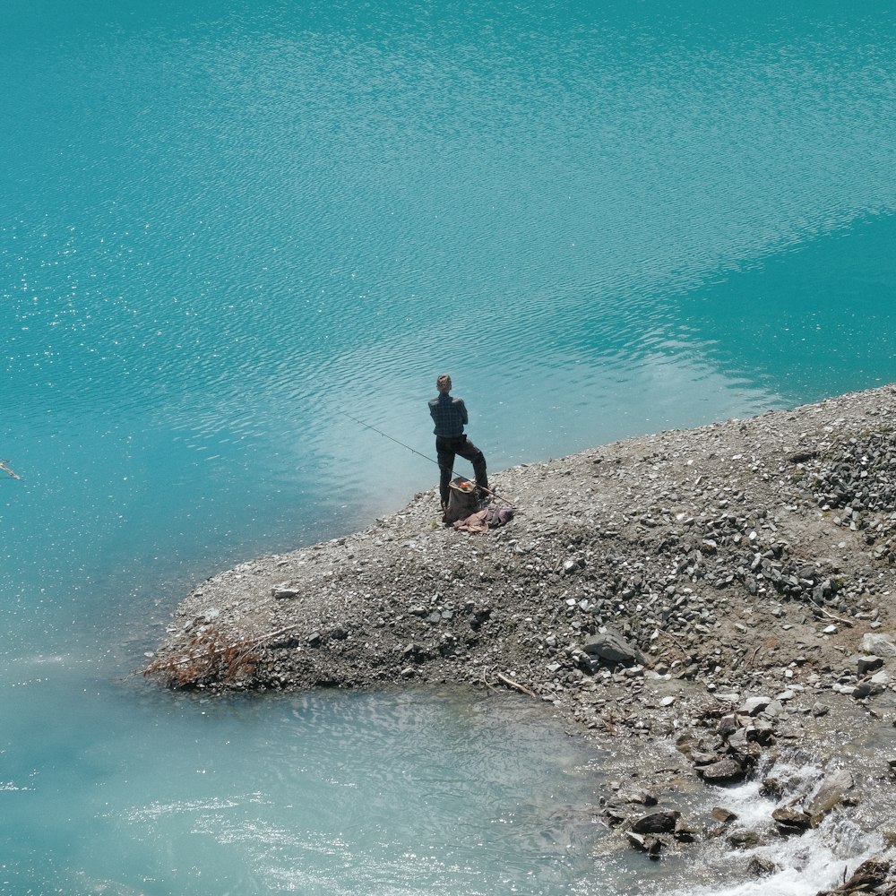 a person fishing on a rocky shore