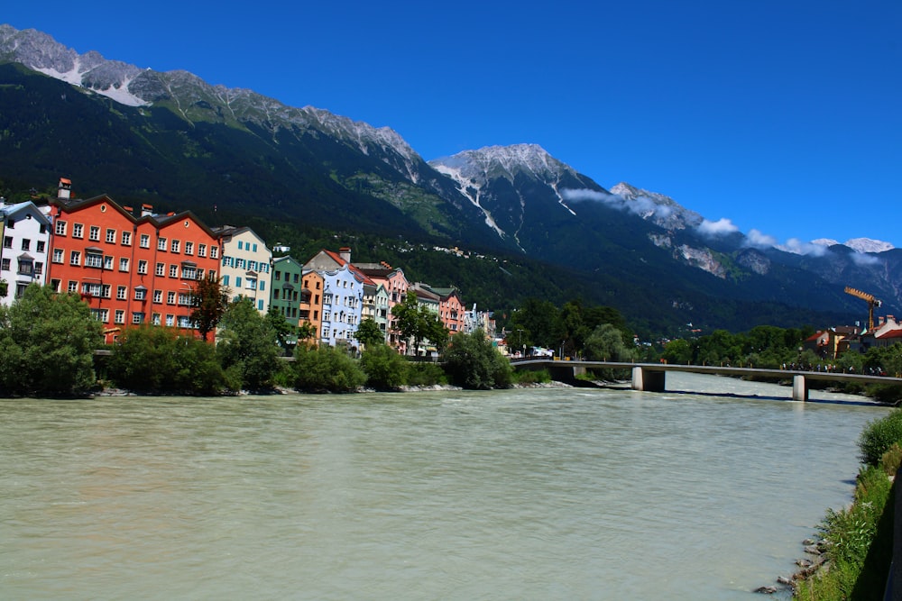 a body of water with buildings along it and mountains in the background