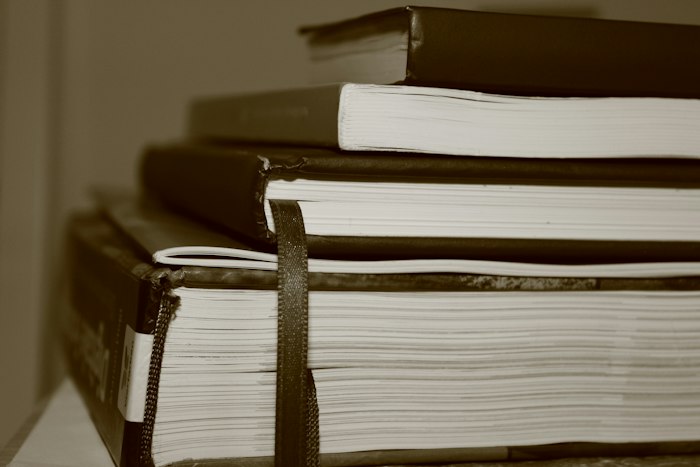 Stack of thick bound books with a ribbon bookmark