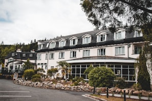 Exterior of a charming hotel building surrounded by greenery on a sunny day.
