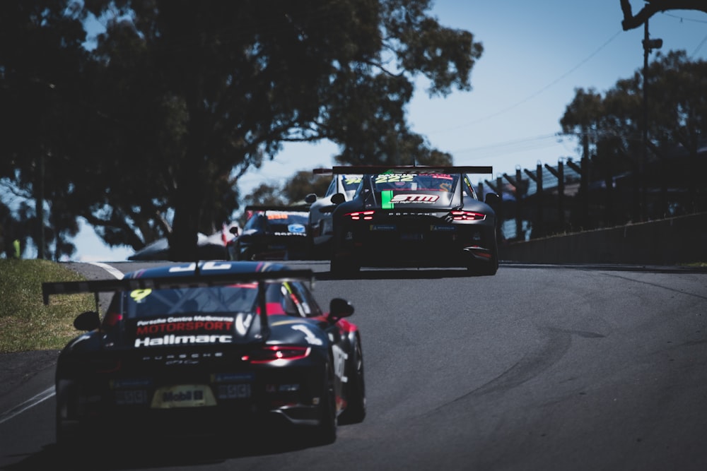 a couple of race cars on a road with trees on either side