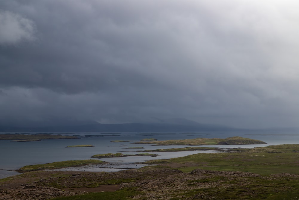 a body of water with land around it and a cloudy sky above