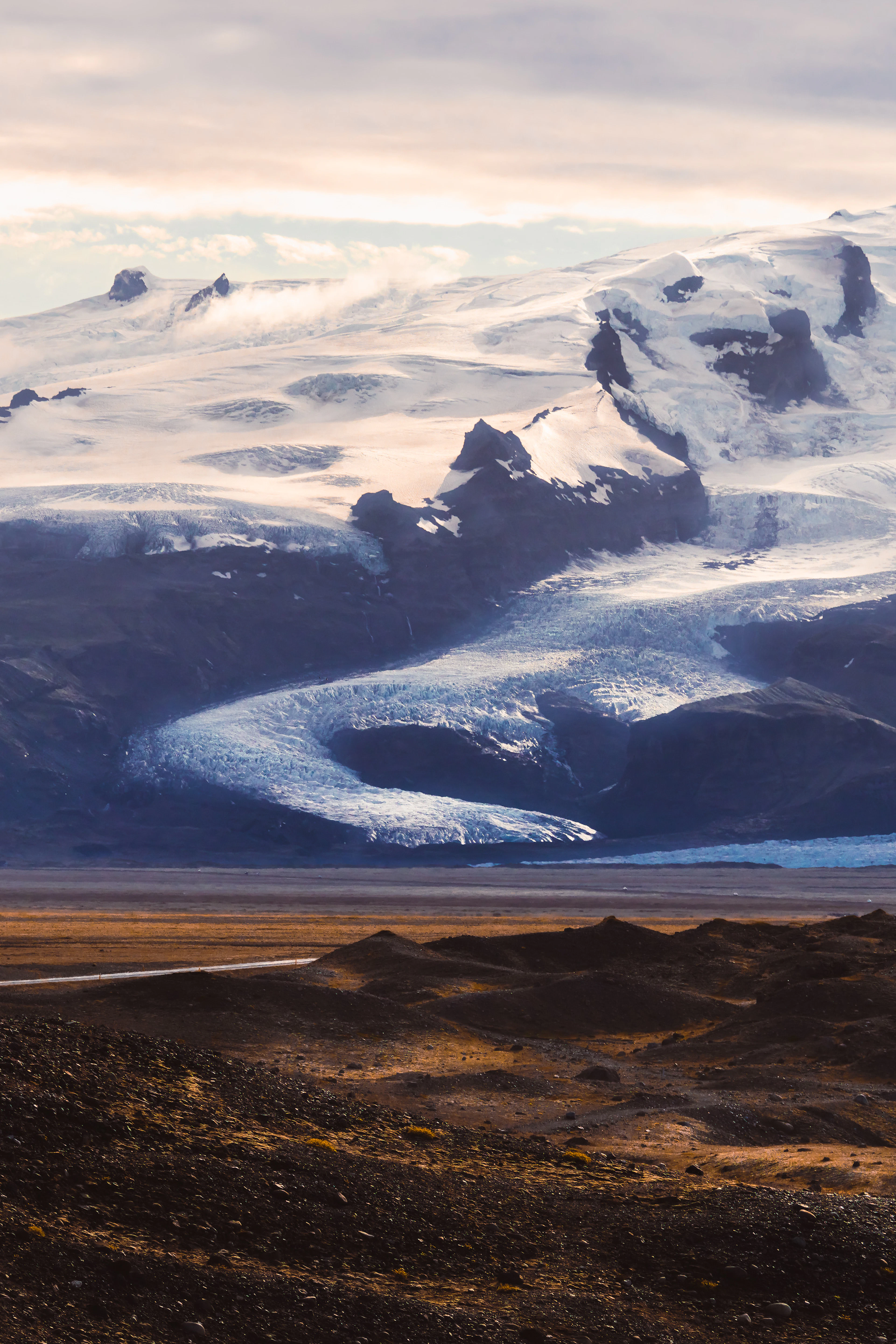 An outlet glacier winds down from Vatnajokull's icefield into a dark volcanic plain.