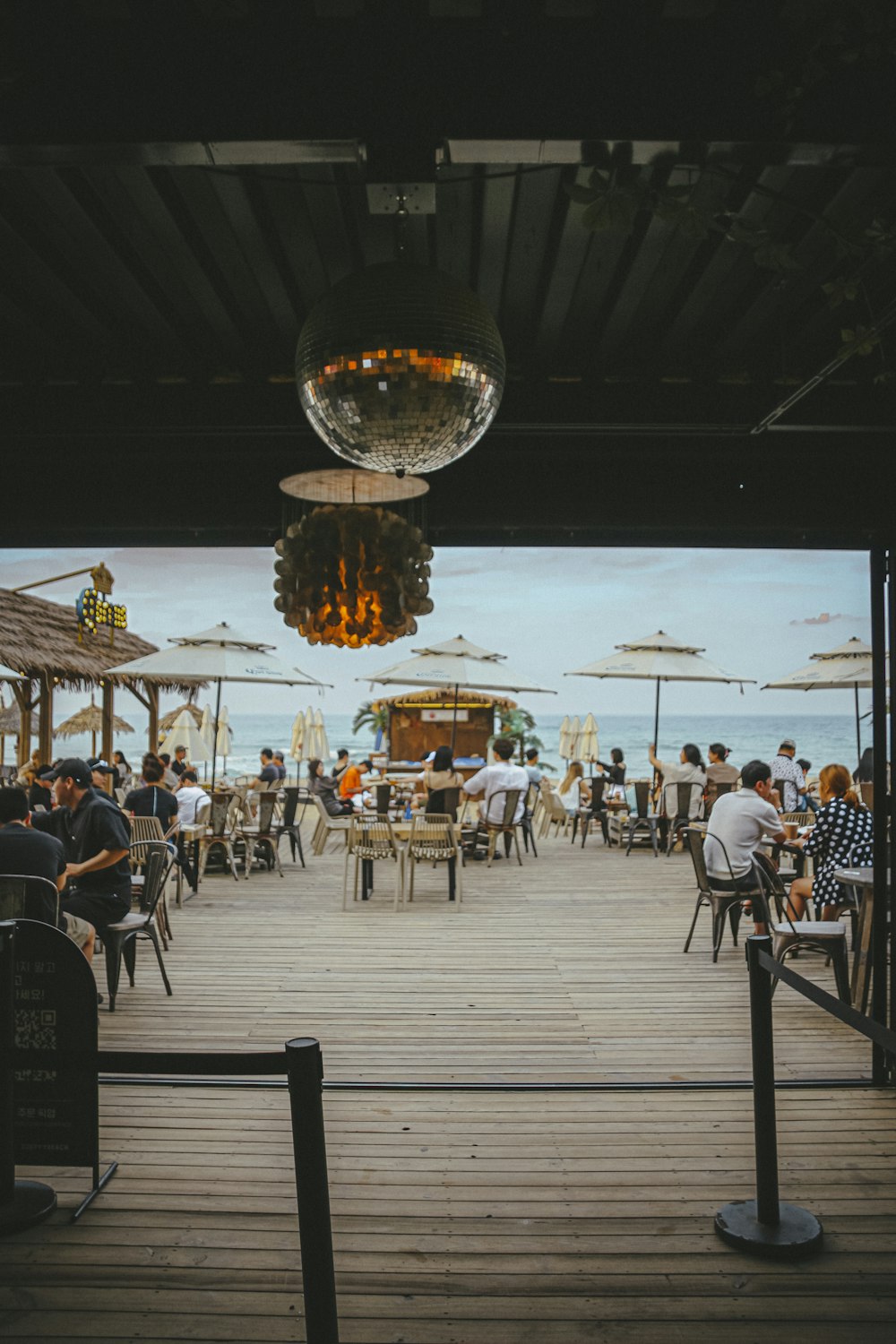 a group of people sitting at tables on a dock by a body of water