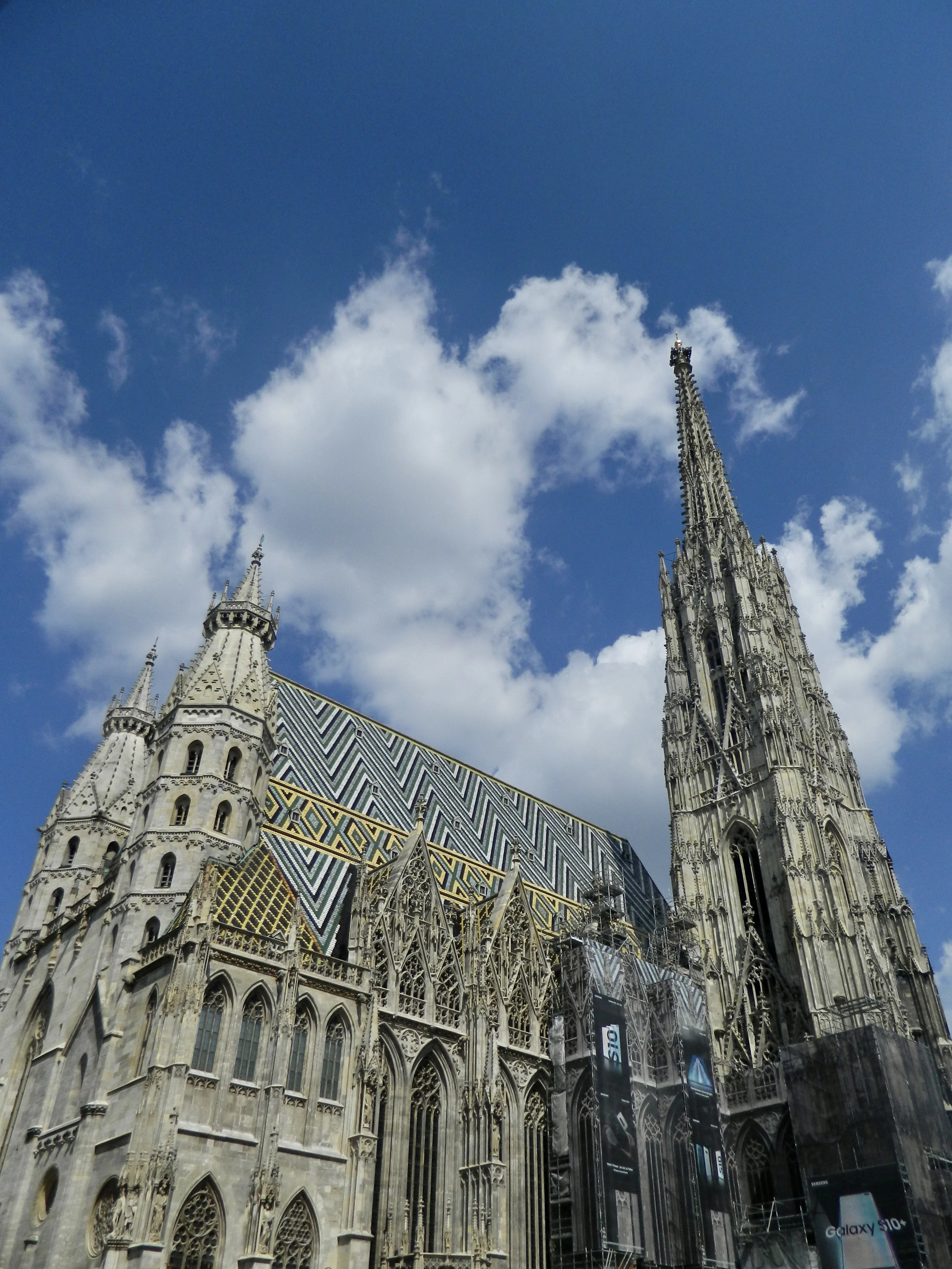 St. Stephen's Cathedral in Vienna against a blue sky, its zigzag-patterned glazed tile roof and Gothic south tower in full sun