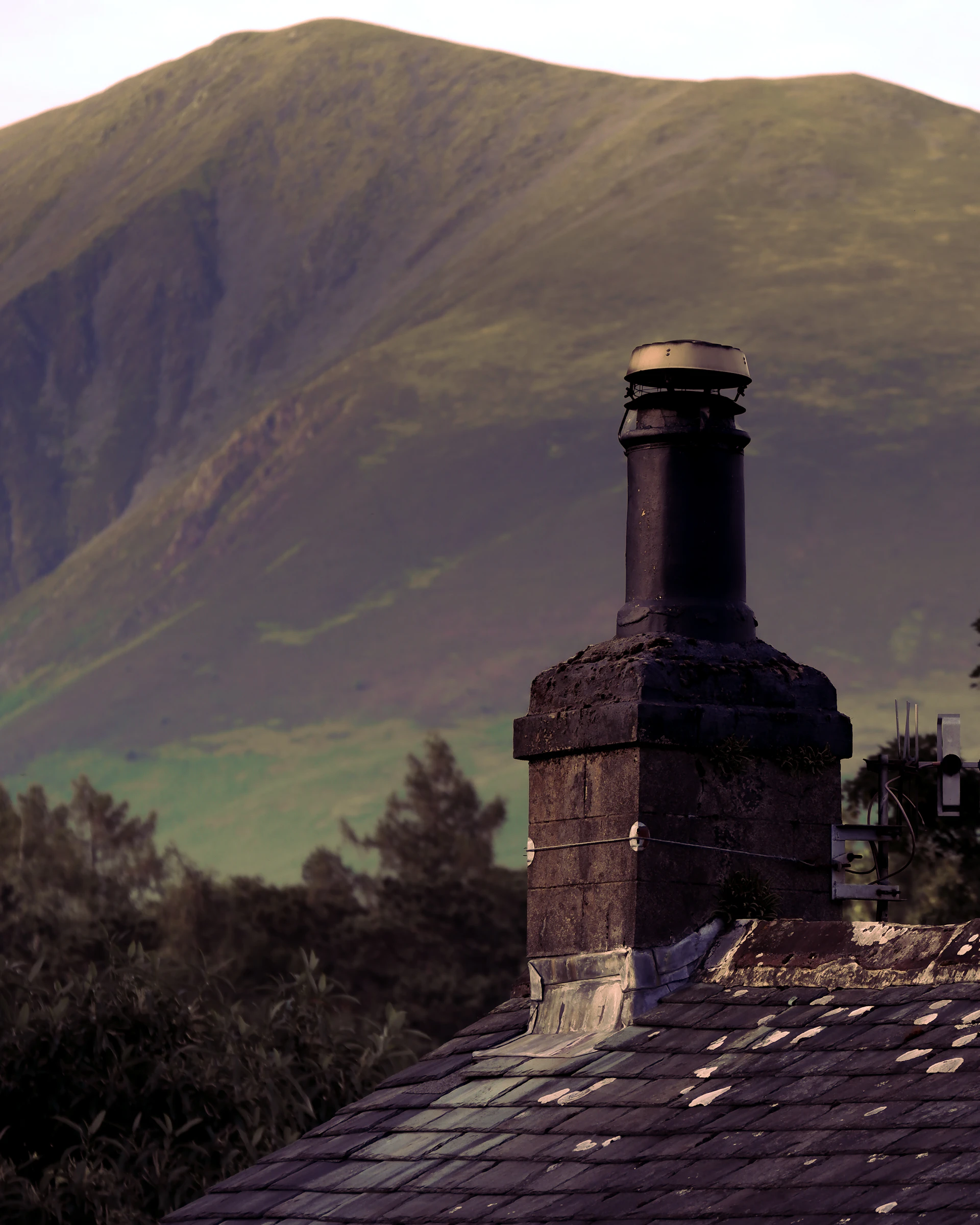 Traditional brick chimney and clay tile roof at dusk in the UK