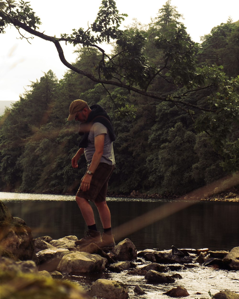 una persona in piedi su una roccia vicino a un fiume