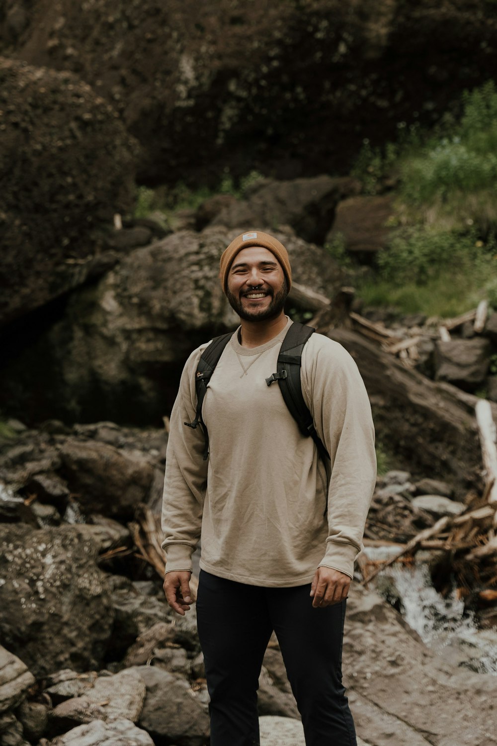 a man wearing a hat and standing in a rocky area