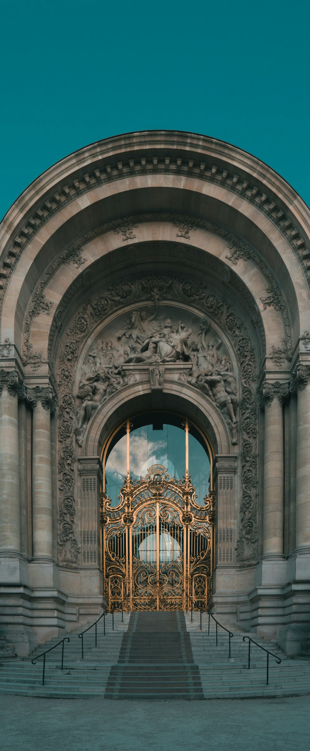 a large arched doorway with a gold door and a gold cross on the top