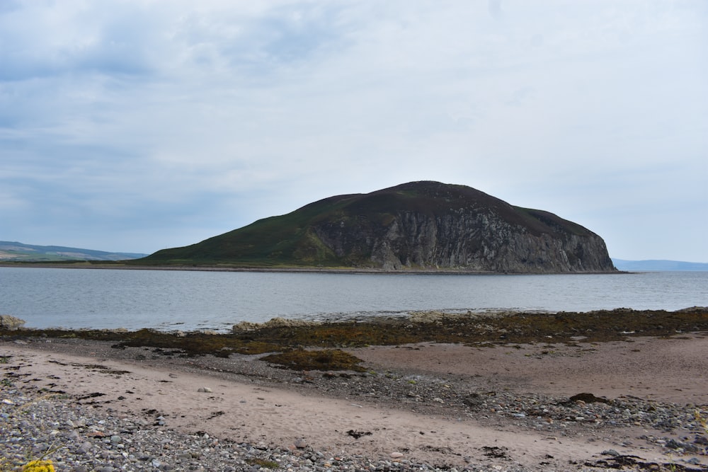 a rocky beach with a large island in the distance