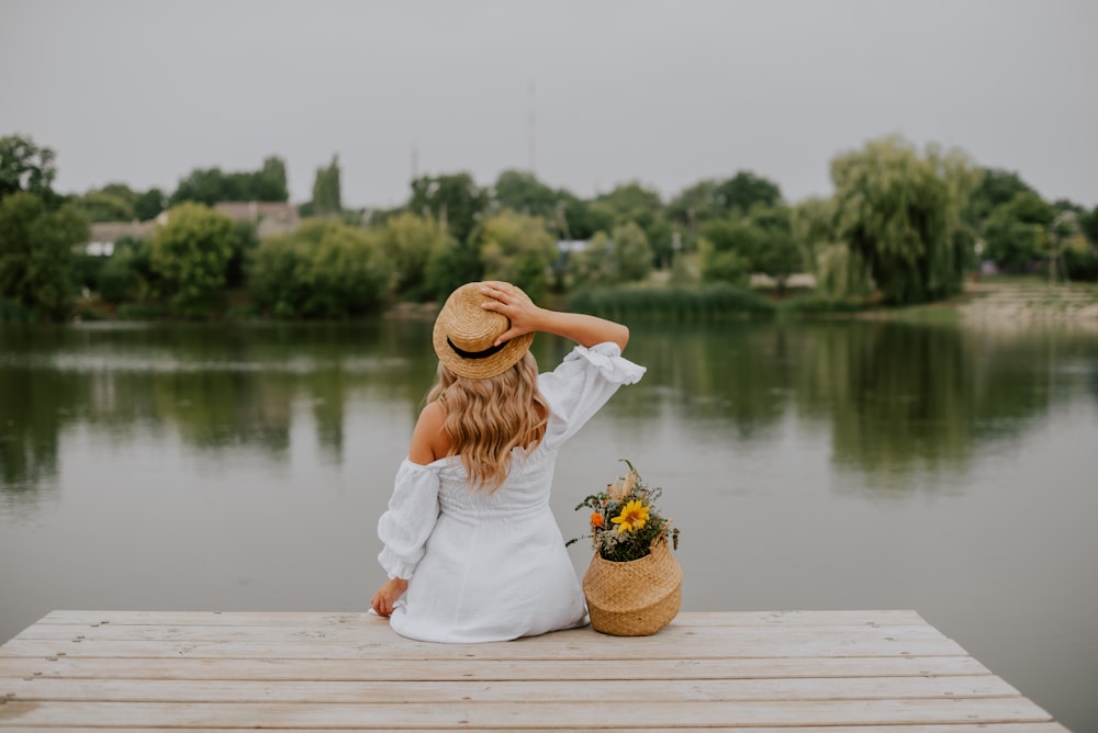 a person sitting on a dock with a basket of flowers