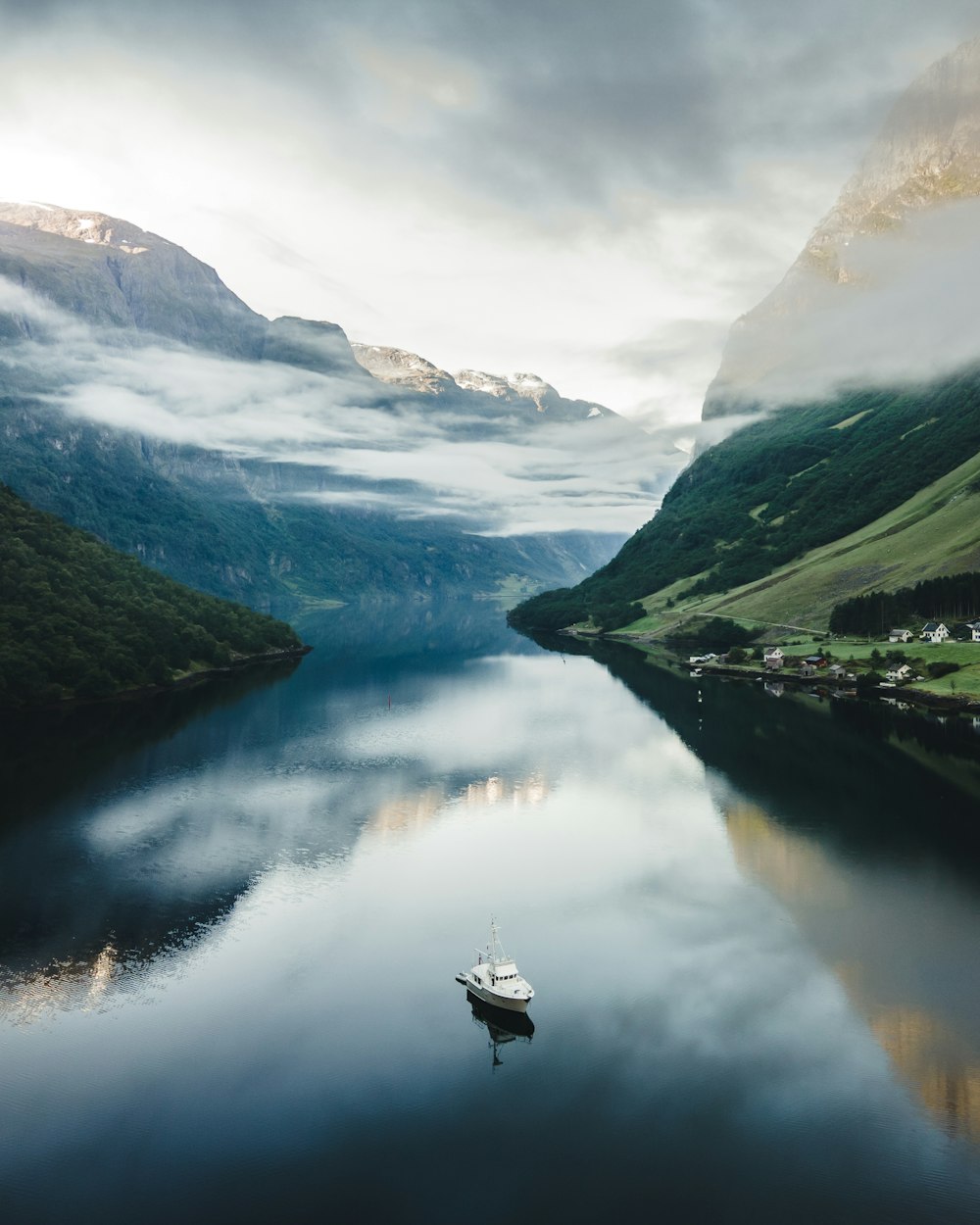 a boat on a lake surrounded by mountains and a cloudy sky