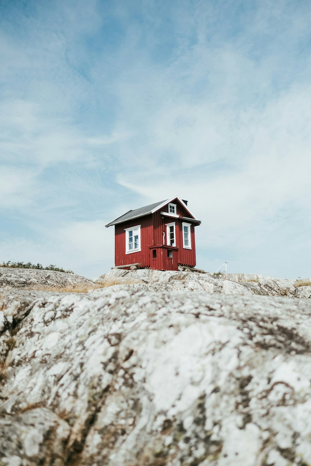 a small red house on a rocky beach