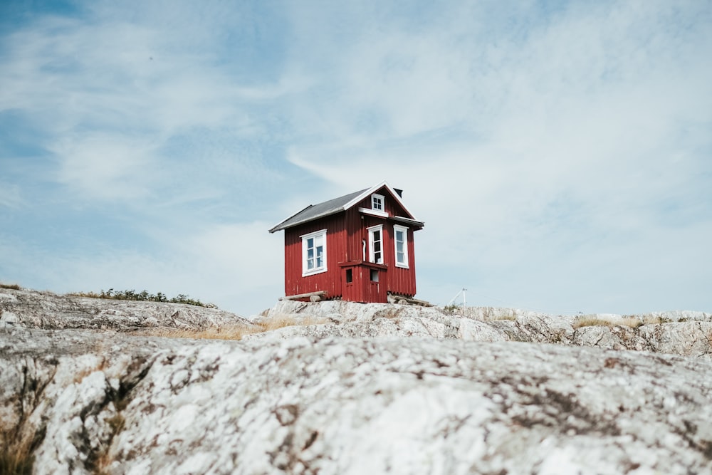 a small red house on a rocky hill