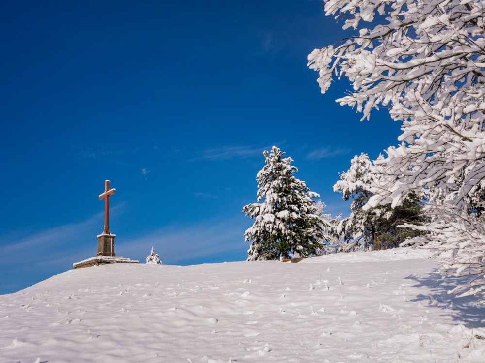a snowy landscape with a cross and trees