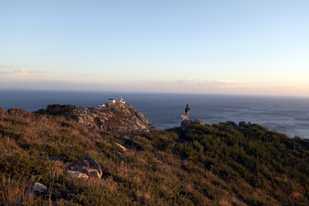 a person standing on a hill overlooking the ocean