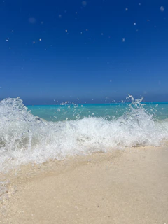 Turquoise waves gently washing onto a pristine sandy beach under a bright sky