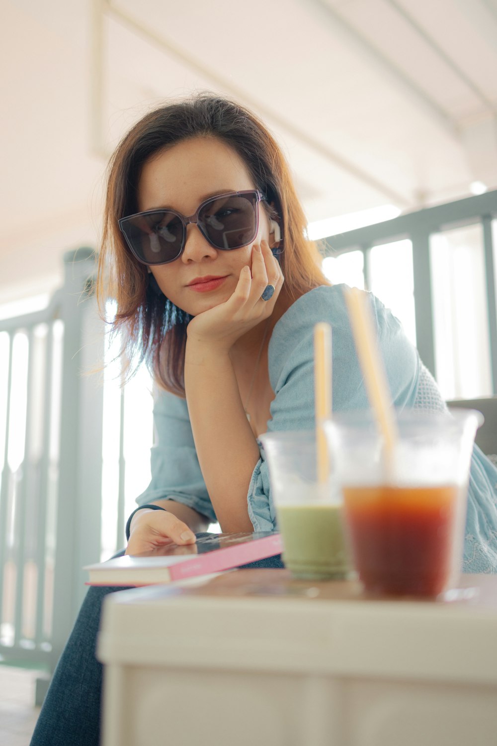 a woman sitting at a table with a drink and a straw
