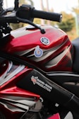 A vibrant red tank cover fitted on a Yamaha motorcycle under sunlight.