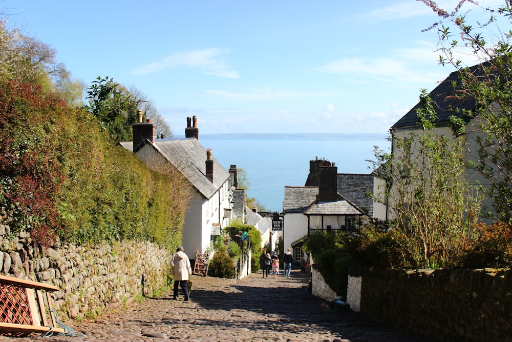 a group of people walking on a path between stone buildings