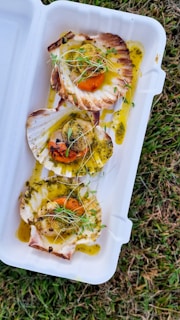 Scallops on half shell with a sprinkle of herbs and a drizzle of sauce