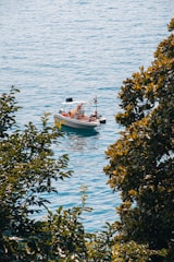 A small boat cruising on a calm lagoon surrounded by lush greenery under a bright blue sky.
