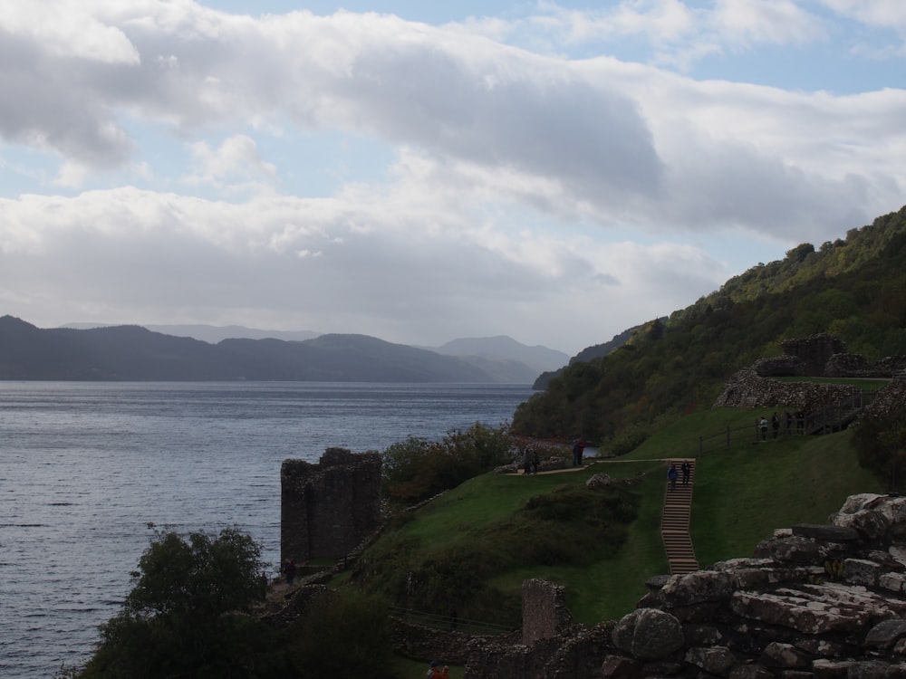 a path leading to a body of water with a hill and a walkway