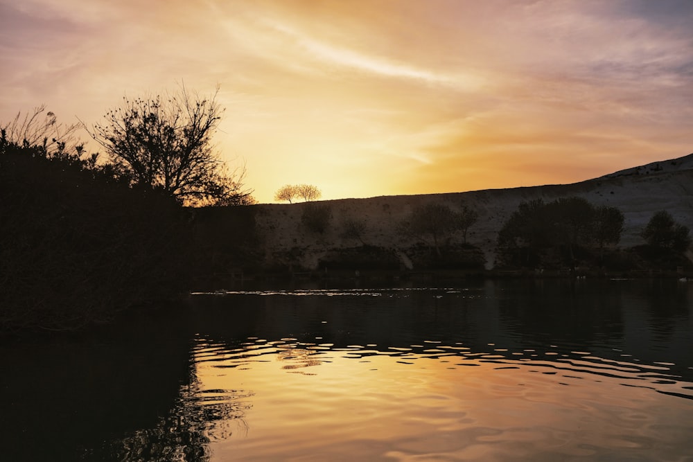 a body of water with trees and hills in the background