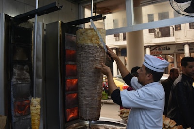 A friendly chef slicing juicy kebabs in a modern kitchen with warm lighting.