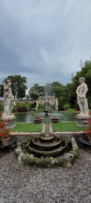 Square image of a quiet garden with blooming flowers and a small fountain.
