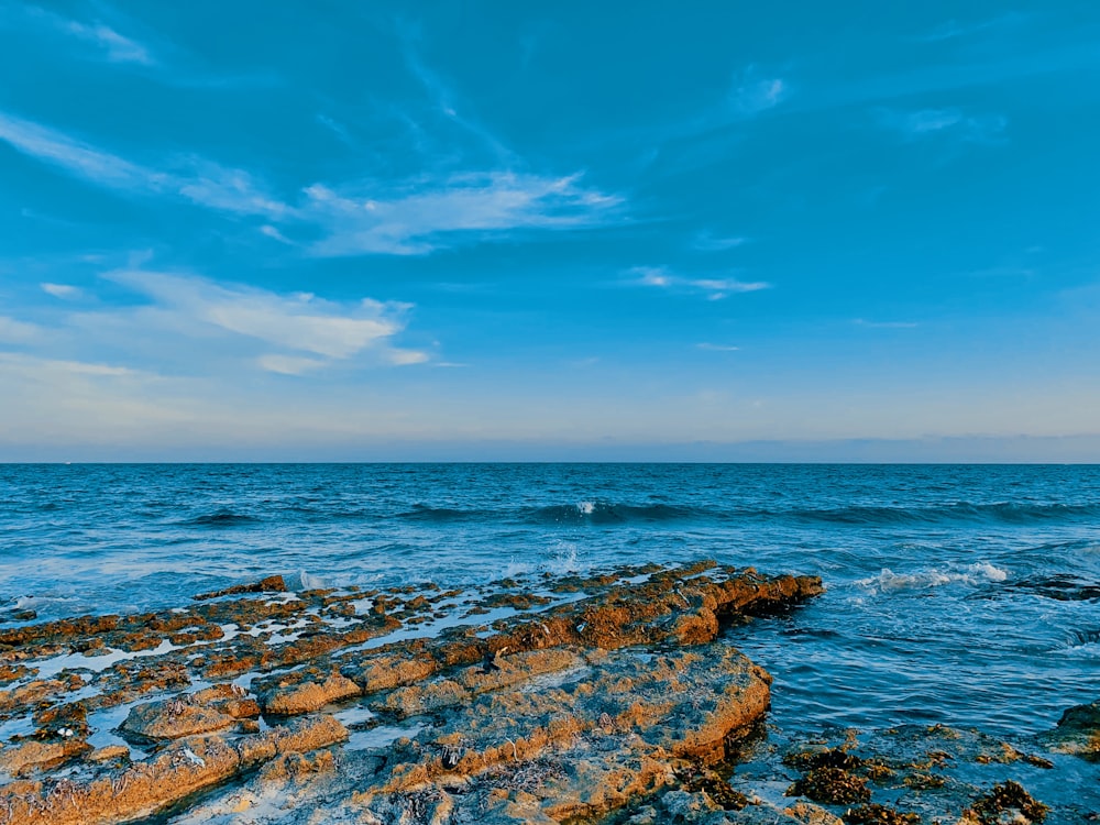 a rocky beach with a body of water in the background