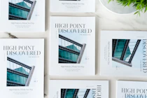 Multiple copies of 'High Point Discovered' magazines arranged on a light surface, featuring a modern architectural building on the cover.