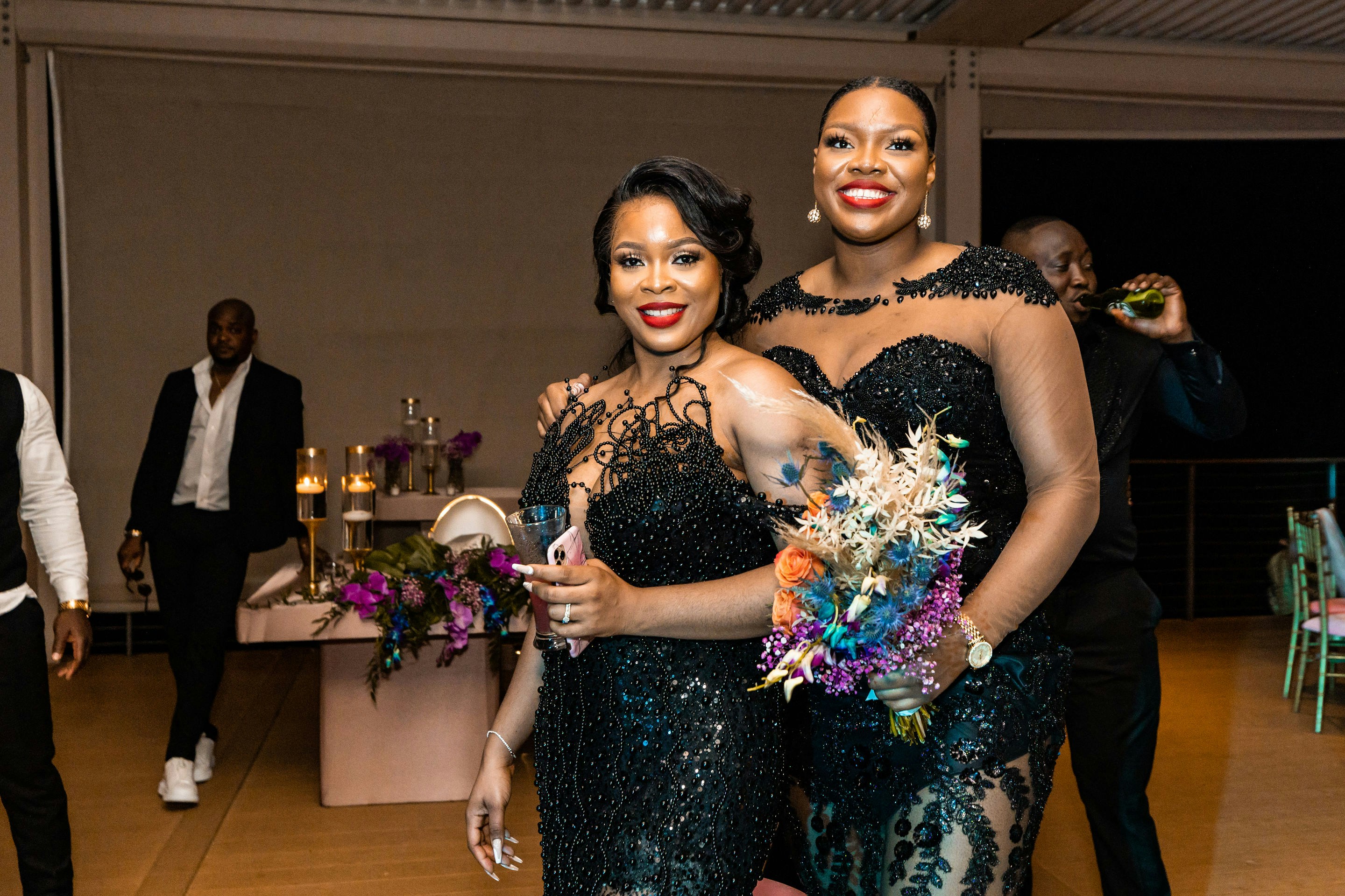 Two women in beaded formal dresses pose at a gala.