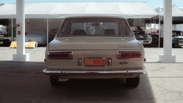 A vintage car parked under a circus tent with colorful flags fluttering above.