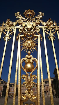 An elegant photograph of Iga Erekọ’s ornate gates framed by deep royal blue skies and antique gold accents.