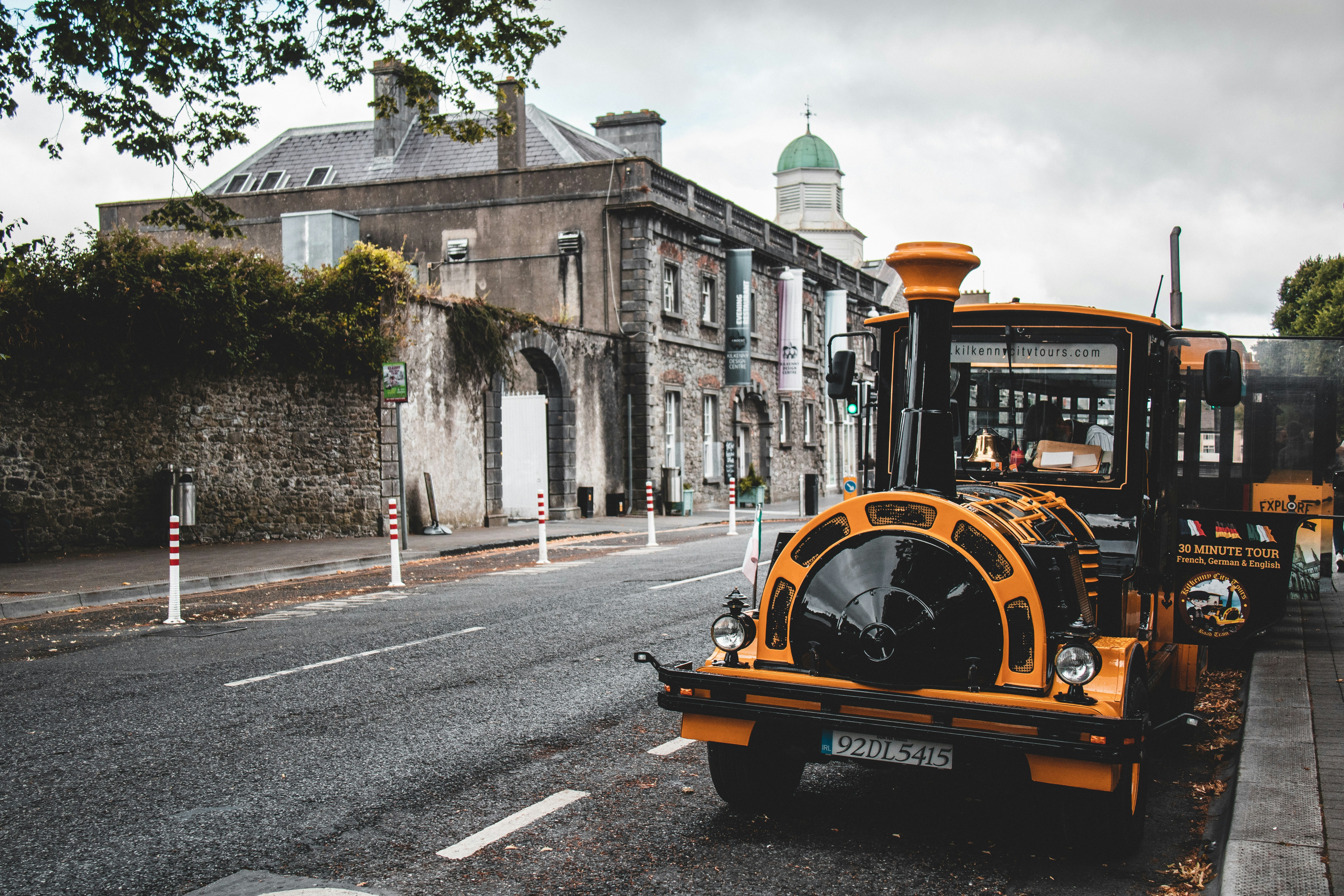 A public transport bus traveling on a busy street in downtown Kilkenny during the day