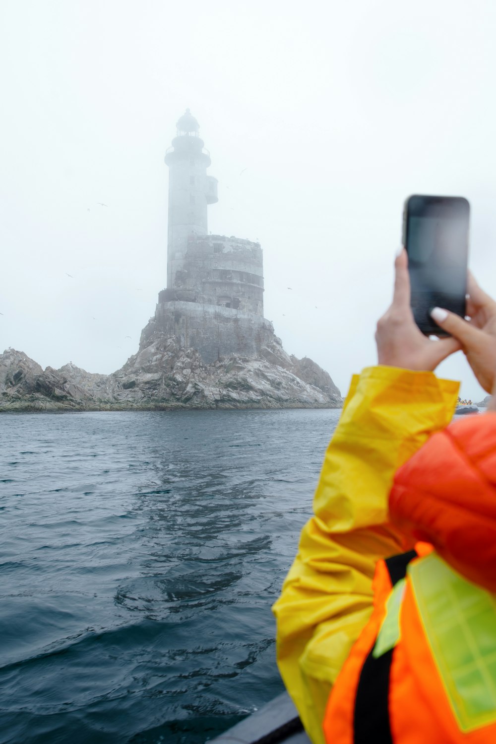 a person taking a picture of a large rock structure in the water