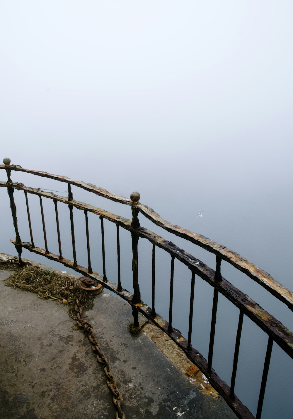 a railing with a railing and a body of water in the background