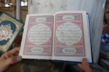A close-up of a hand holding an open book with intricate designs.