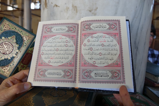 A close-up of a hand holding an open book with intricate designs.