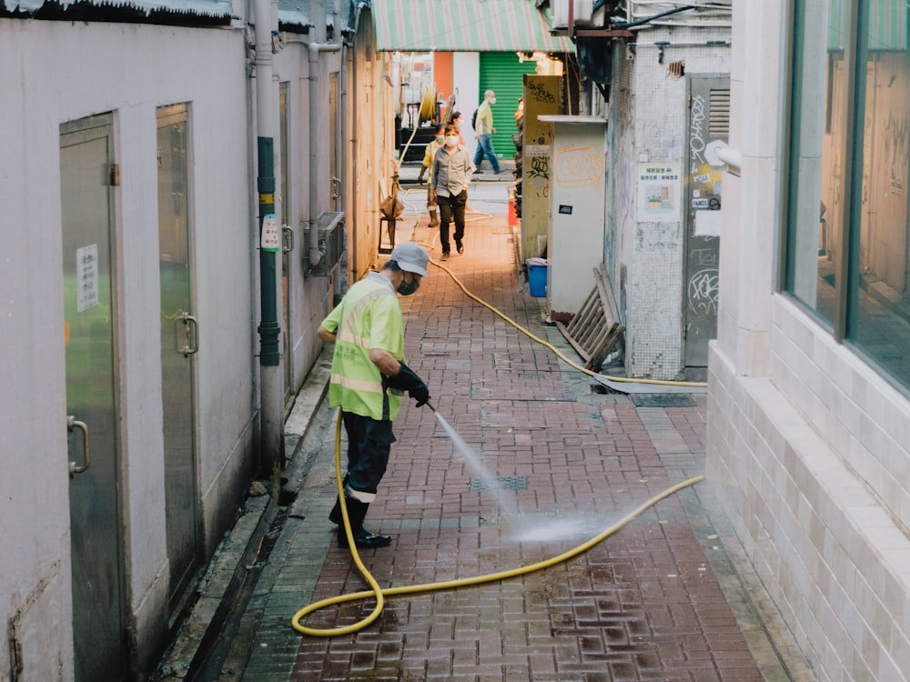 a person in a safety vest working on a hose in a narrow alley